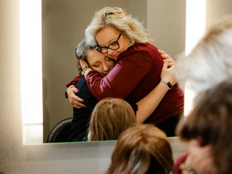 Two women hugging while getting a wig